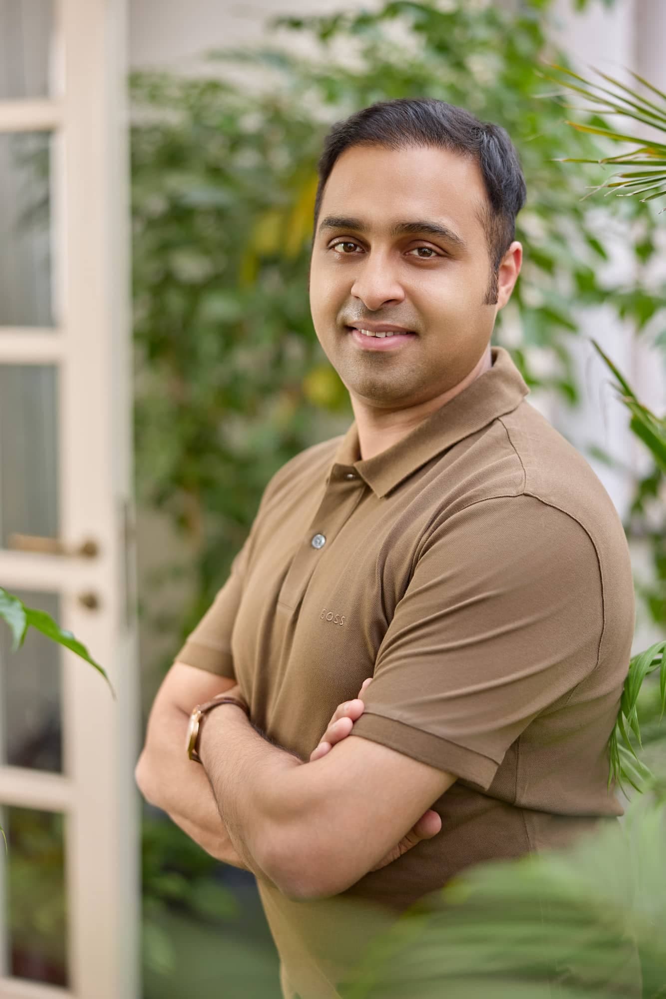 Entrepreneur in an olive polo shirt with greenery behind — relaxed branding portrait