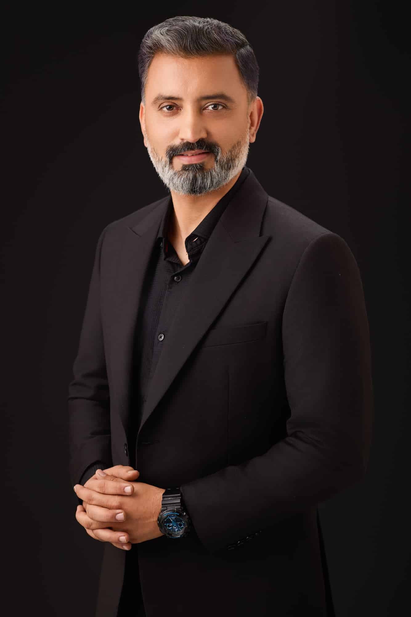 Executive in a black suit on a dark studio backdrop — business portrait photography by Imagesque, Dubai