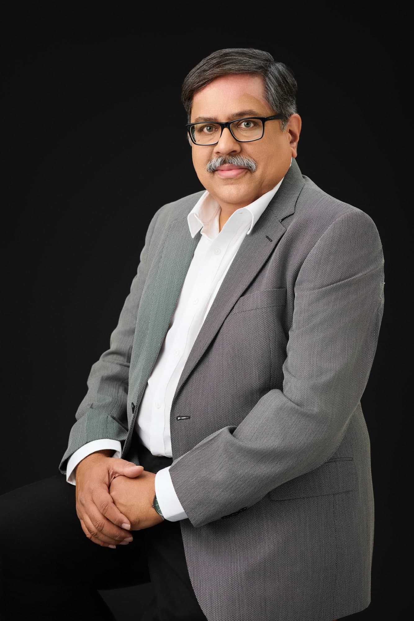 Senior executive in a grey jacket on a dark backdrop — business portrait photography by Imagesque, Dubai