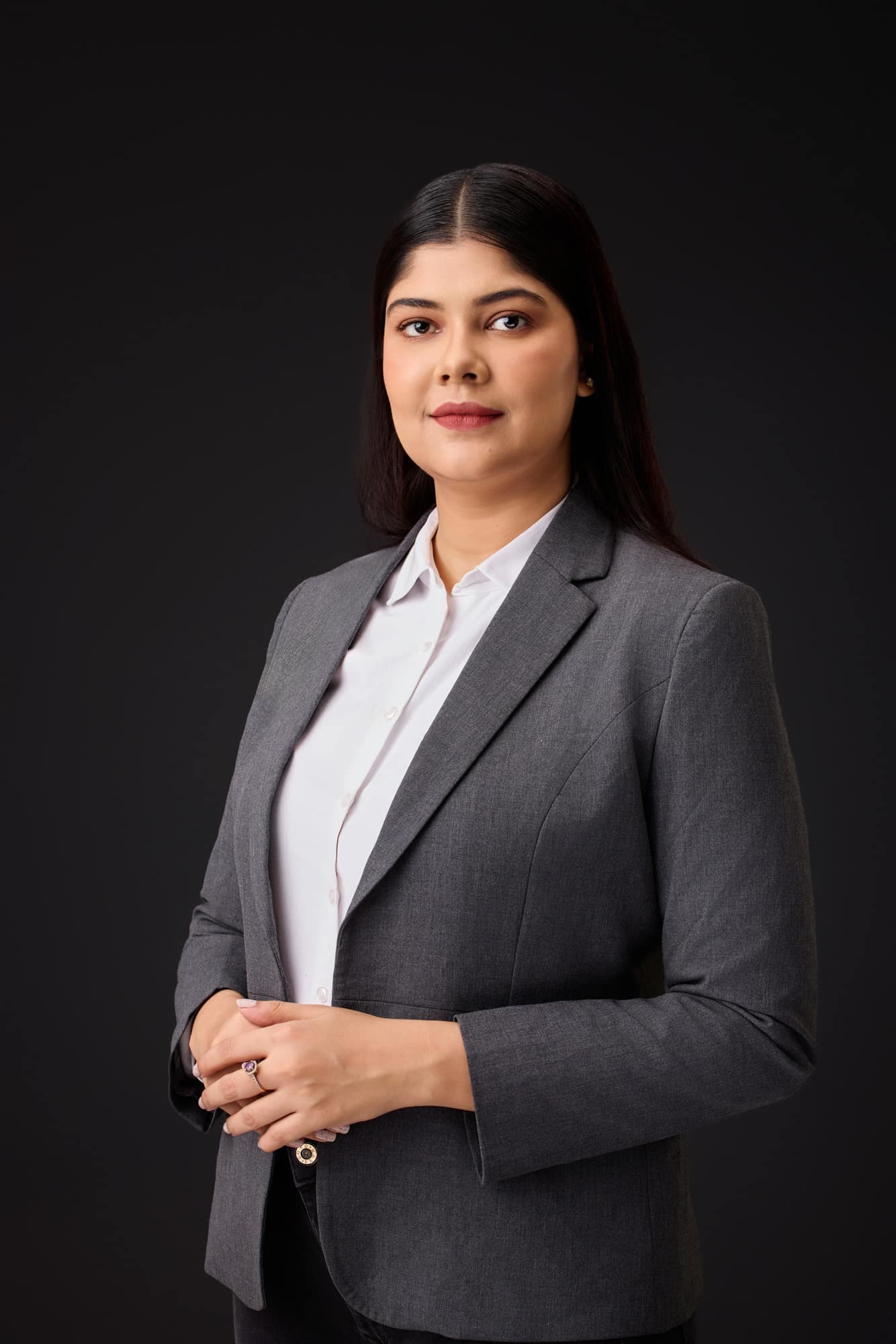 Professional woman in a grey blazer, corporate headshot on a dark backdrop — business portrait photography by Imagesque, Dubai