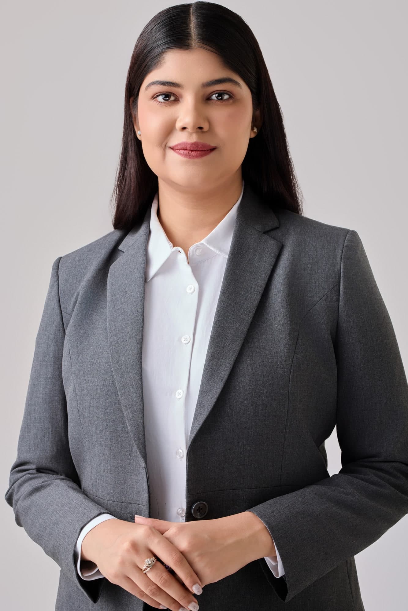 Professional woman in a grey blazer on a light grey backdrop — business portrait photography by Imagesque, Dubai