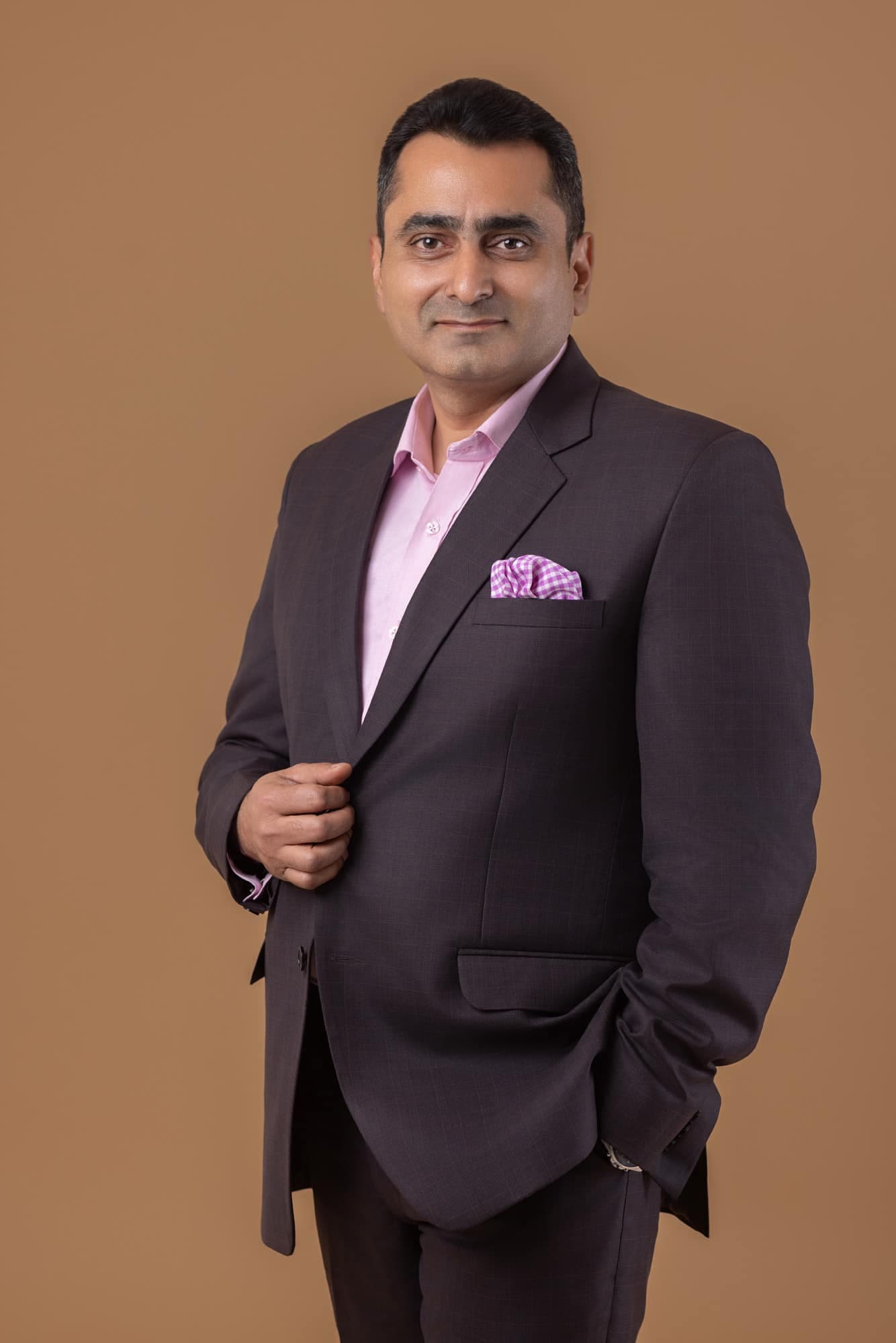 Executive in a dark blazer on a warm tan backdrop — business portrait photography by Imagesque, Dubai