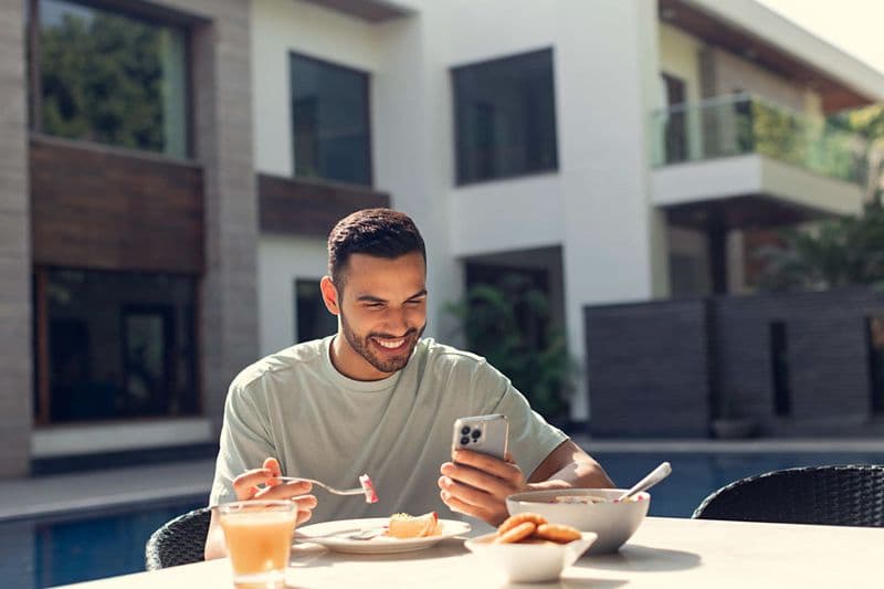 Man enjoying breakfast on a sunlit terrace