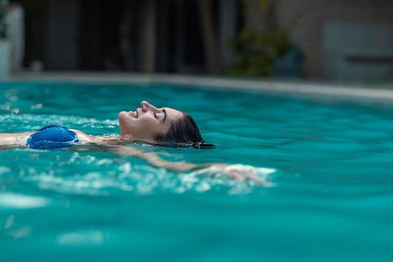 Woman floating in a turquoise pool — luxury travel lifestyle photography